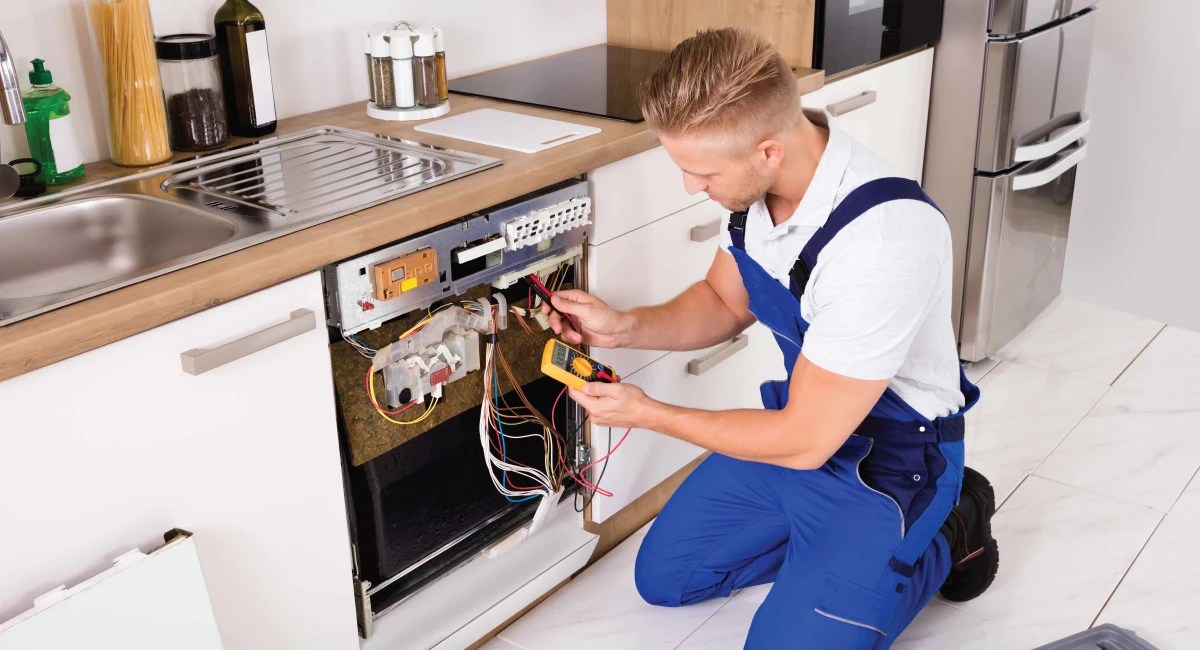 Technician checking the wiring behind an open dishwasher door