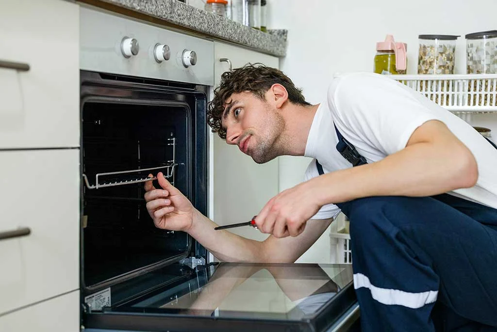 Technician inspecting the inside of a built-in kitchen oven