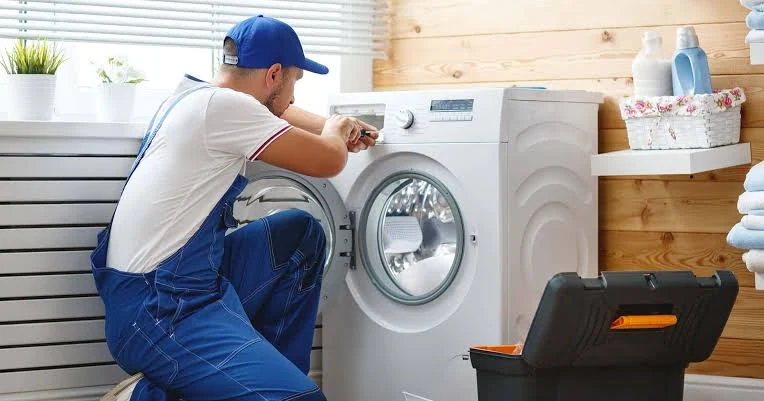 Technician checking the controls of a front-loading washing machine
